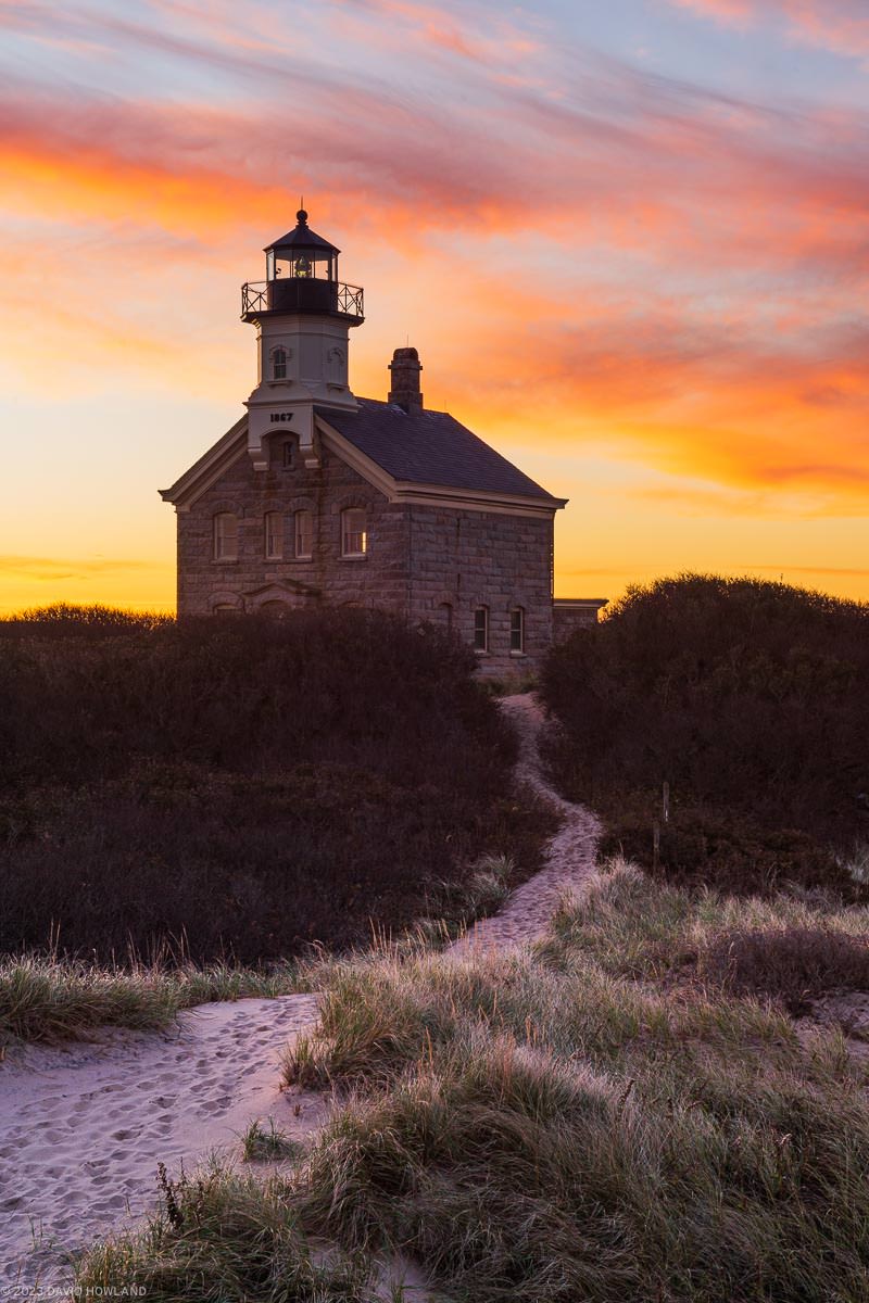 A photo of colorful clouds silhouetting North Lighthouse on Block Island at sunrise