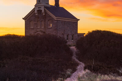 A photo of colorful clouds silhouetting North Lighthouse on Block Island at sunrise